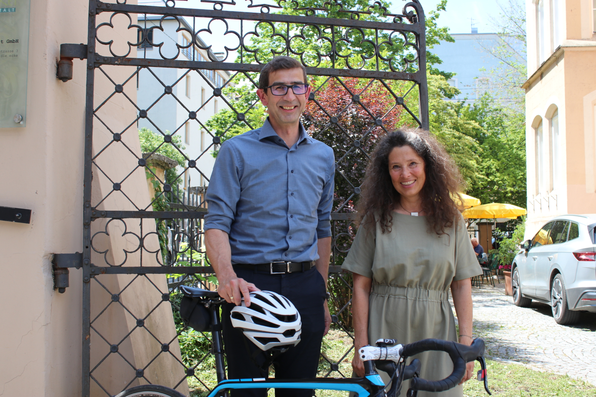 Mann mit Fahrradhelm in der Hand und Frau lachen in die Kamera