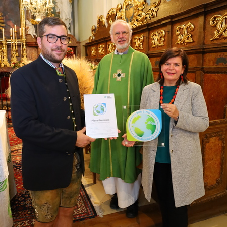 Der Pfarrer, der Pfarrgemeinderat und Petra Schön vom Klimabündnis stehen mit der Mitglieder-Tafel in der Kirche.