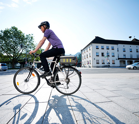 Eine Person radelt über einen Platz im Hintergrund sieht man kaum Verkehr und mehrere Gebäude