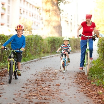zwei Kinder und eine erwachsene Person haben sichtlich Spaß beim Radfahren