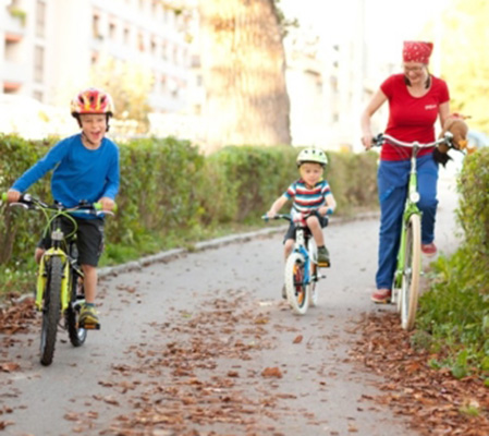 zwei Kinder und eine erwachsene Person fahren Rad und haben sichtlich Spaß