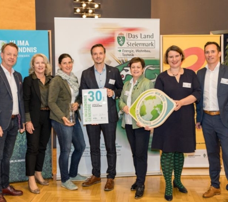 Klimabündnis Auszeichnungsgala: Gemeindevertreter stehen mit Vorständen vor dem Klimabündnis und Land Steiermark Rollup und lächeln. Sie halten die Auszeichnungen in den Händen.