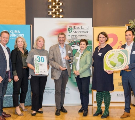 Klimabündnis Auszeichnungsgala: Gemeindevertreter stehen mit Vorständen vor dem Klimabündnis und Land Steiermark Rollup und lächeln. Sie halten die Auszeichnungen in den Händen.