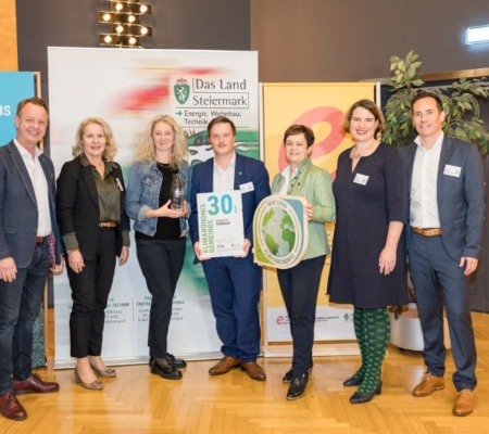 Klimabündnis Auszeichnungsgala: Gemeindevertreter stehen mit Vorständen vor dem Klimabündnis und Land Steiermark Rollup und lächeln. Sie halten die Auszeichnungen in den Händen.
