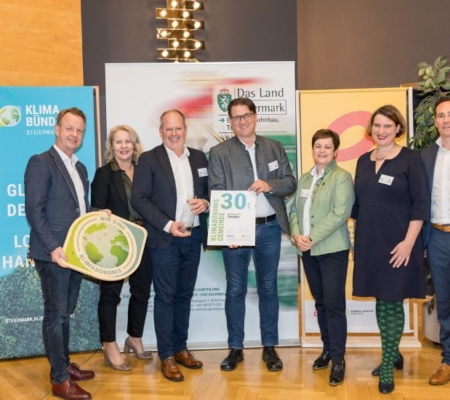 Klimabündnis Auszeichnungsgala: Gemeindevertreter stehen mit Vorständen vor dem Klimabündnis und Land Steiermark Rollup und lächeln. Sie halten die Auszeichnungen in den Händen.