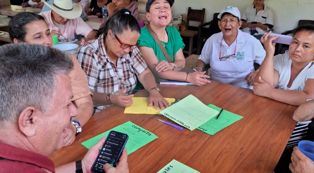 Menschen sitzen um einen Tisch lachend und redend zusammen