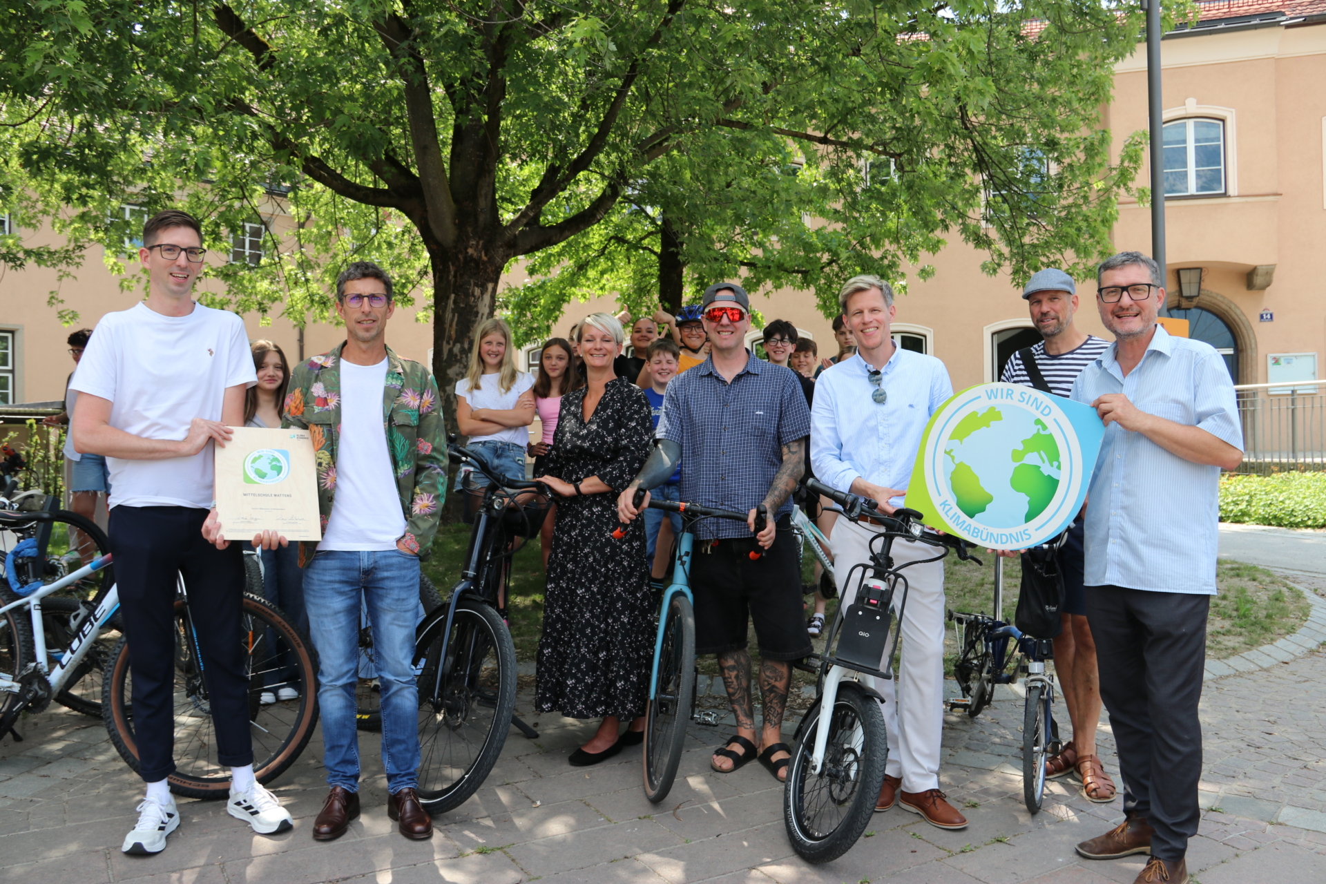 Erwachsene mit Fahrrädern halten eine Urkunde und eine Logo in der Hand