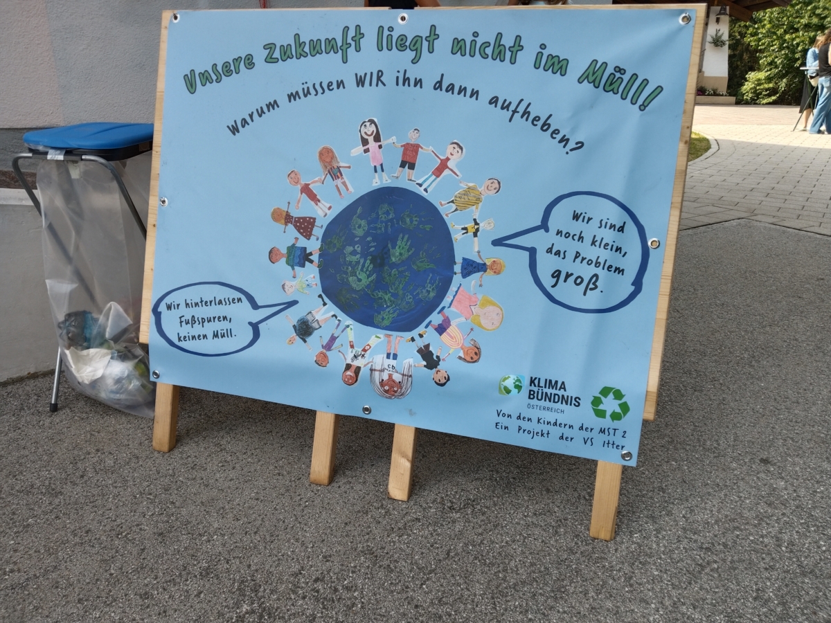 Ein Plakat neben einem Müllkübel weist auf Müllthema hin