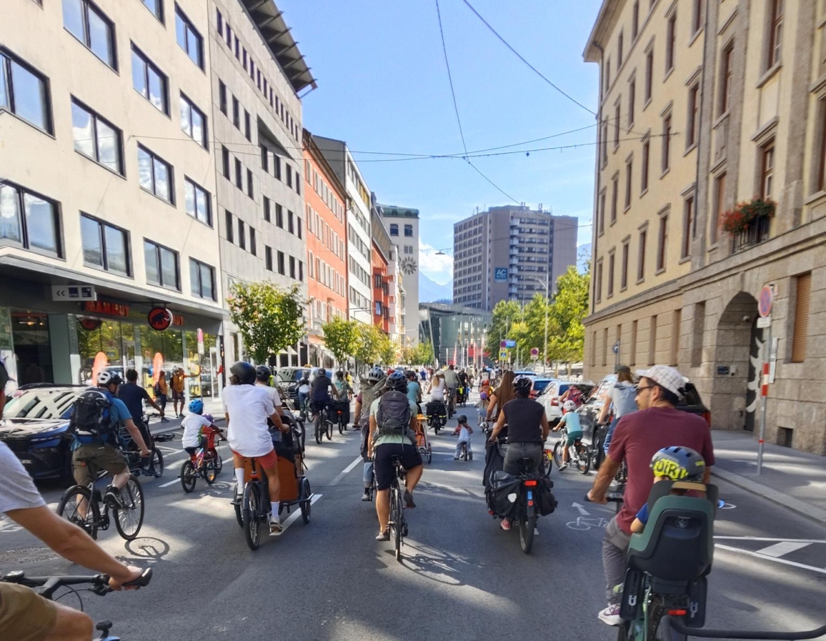 Erwachsene und Kinder fahren als Gruppe mit Rädern durch eine Straße